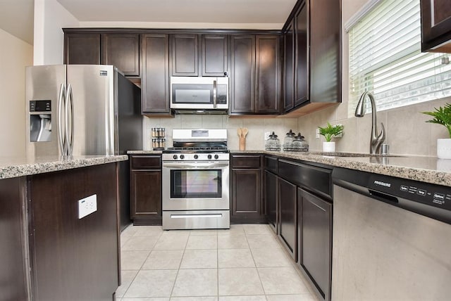 3514 Marquesa Ln, Houston, TX 77084 - kitchen with stainless steel appliances, backsplash, light stone counters, and dark brown cabinets
