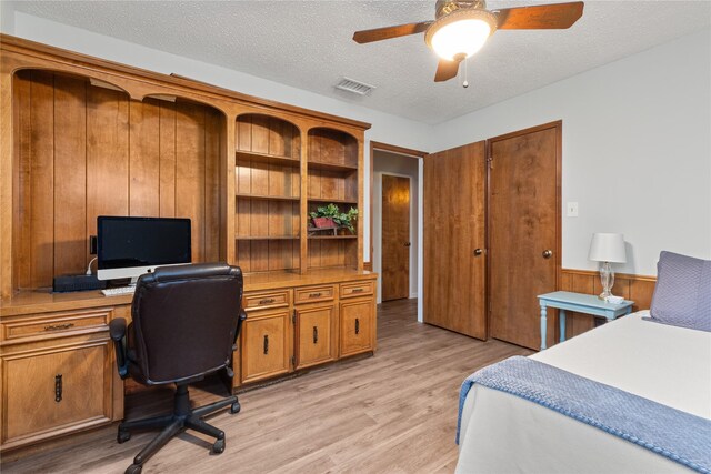 2006 Echo Ridge Ct, Houston, TX 77339 - bedroom featuring light wood-type flooring, an office area, a textured ceiling, wooden walls, and a ceiling fan