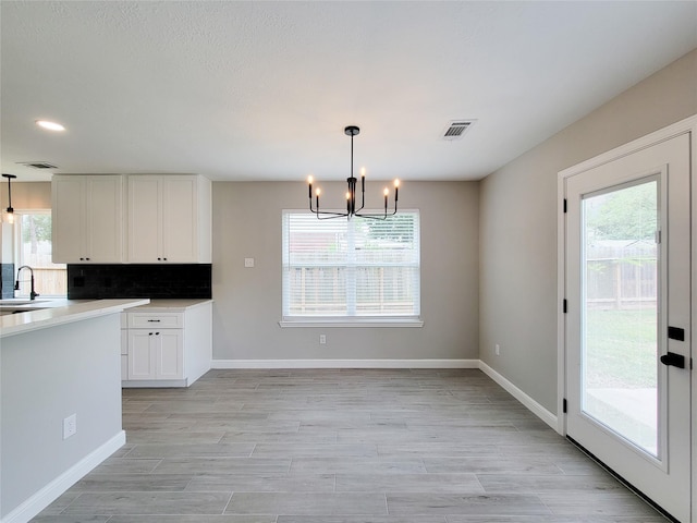 18106 Water Mill Dr, Cypress, TX 77429 - kitchen featuring a chandelier, healthy amount of natural light, white cabinets, tasteful backsplash, and recessed lighting