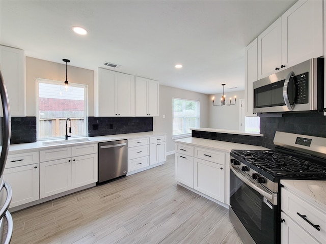 18106 Water Mill Dr, Cypress, TX 77429 - kitchen with appliances with stainless steel finishes, a chandelier, decorative backsplash, white cabinetry, and recessed lighting