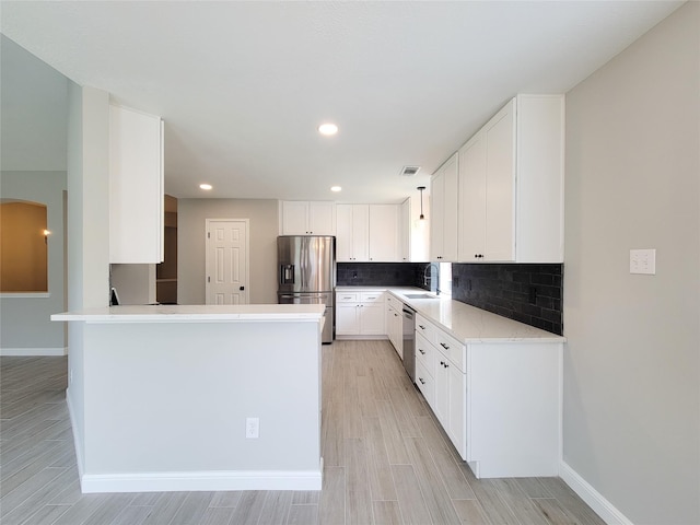 18106 Water Mill Dr, Cypress, TX 77429 - kitchen with stainless steel appliances, a peninsula, backsplash, white cabinets, and recessed lighting