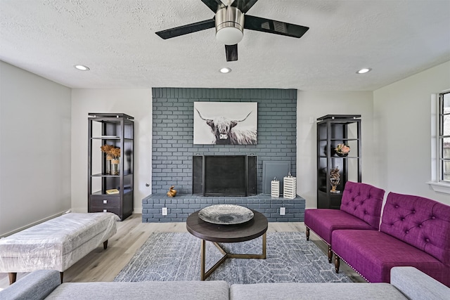 1201 Shady Oak Ln, Dickinson, TX 77539 - living room with wood finished floors, a textured ceiling, a ceiling fan, recessed lighting, and a brick fireplace