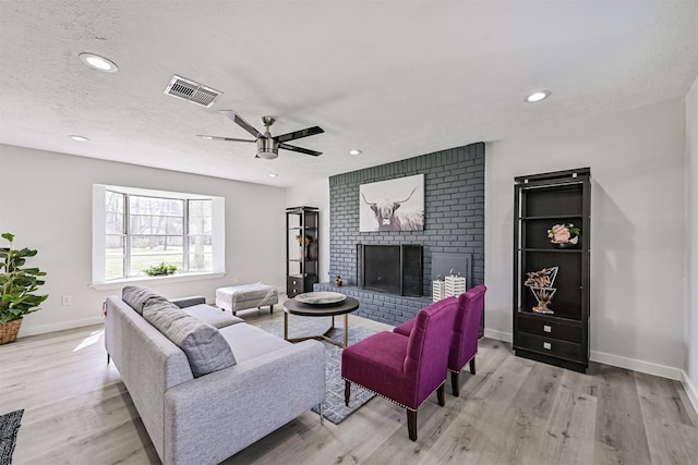 1201 Shady Oak Ln, Dickinson, TX 77539 - living room featuring light wood-type flooring, a fireplace, recessed lighting, a ceiling fan, and a textured ceiling