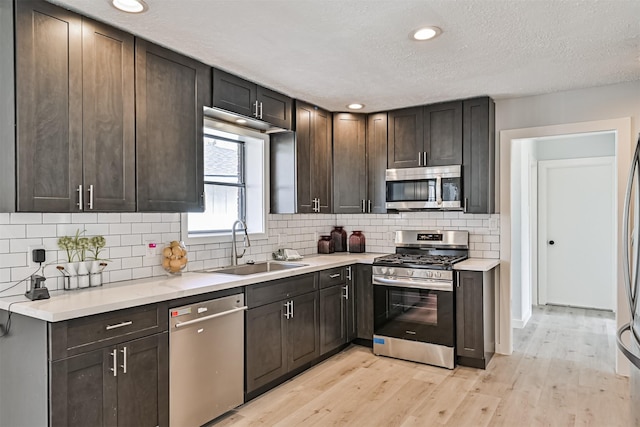 1201 Shady Oak Ln, Dickinson, TX 77539 - kitchen featuring appliances with stainless steel finishes, light countertops, backsplash, light wood-type flooring, and a textured ceiling