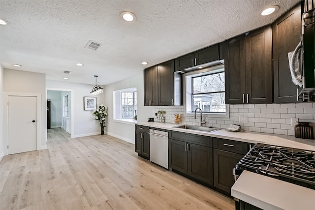 1201 Shady Oak Ln, Dickinson, TX 77539 - kitchen featuring appliances with stainless steel finishes, light countertops, decorative backsplash, a textured ceiling, and light wood-style floors