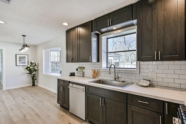 1201 Shady Oak Ln, Dickinson, TX 77539 - kitchen with stainless steel dishwasher, decorative backsplash, light wood-style floors, a textured ceiling, and hanging light fixtures
