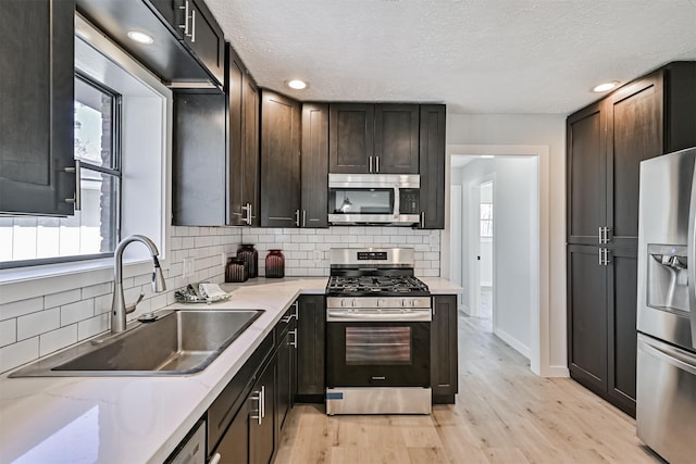 1201 Shady Oak Ln, Dickinson, TX 77539 - kitchen featuring stainless steel appliances, tasteful backsplash, light wood-style flooring, a textured ceiling, and light stone countertops