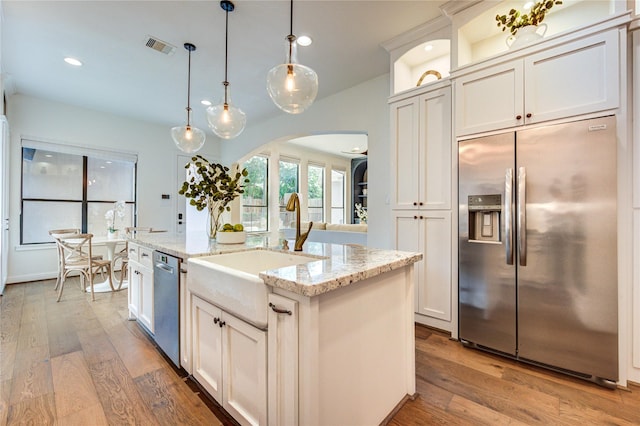 1403 Wakefield Dr, Houston, TX 77018 - kitchen with appliances with stainless steel finishes, arched walkways, white cabinetry, light wood-style floors, and recessed lighting