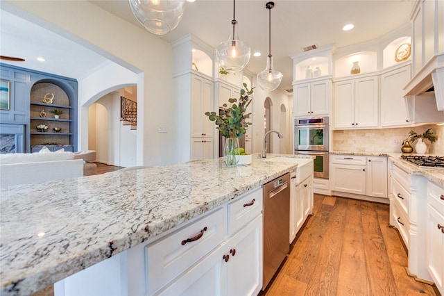 1403 Wakefield Dr, Houston, TX 77018 - kitchen with appliances with stainless steel finishes, arched walkways, white cabinets, glass insert cabinets, and light stone counters
