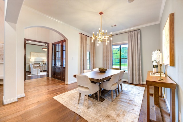 1403 Wakefield Dr, Houston, TX 77018 - dining space with arched walkways, light wood finished floors, a chandelier, and crown molding