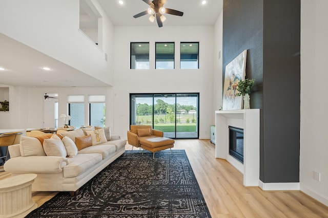 6618 Mirabeau Ln, Katy, TX 77493 - living area featuring a ceiling fan, wood finished floors, a glass covered fireplace, recessed lighting, and a high ceiling