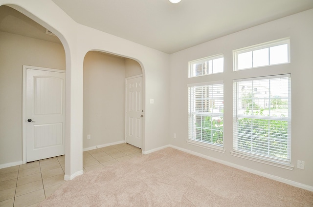 24938 Pavarotti Pl, Katy, TX 77493 - empty room with arched walkways, light tile patterned floors, light carpet, and plenty of natural light