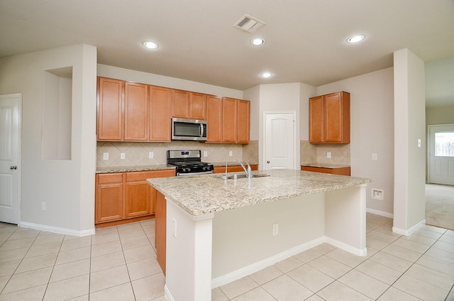 24938 Pavarotti Pl, Katy, TX 77493 - kitchen with appliances with stainless steel finishes, backsplash, a center island with sink, light tile patterned flooring, and recessed lighting