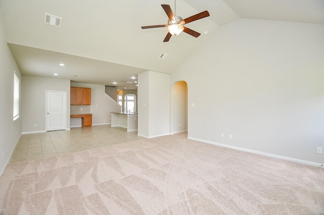 24938 Pavarotti Pl, Katy, TX 77493 - unfurnished living room with a ceiling fan, arched walkways, high vaulted ceiling, light tile patterned flooring, and light colored carpet