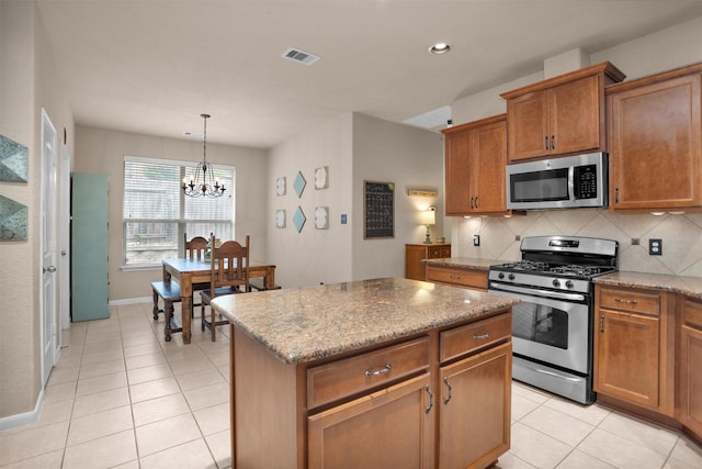 1900 Pagemill Ln, Conroe, TX 77304 - kitchen featuring appliances with stainless steel finishes, a chandelier, brown cabinets, decorative backsplash, and light tile patterned floors