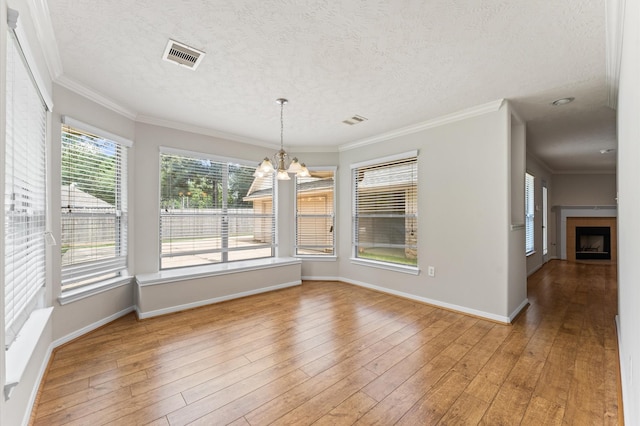 14607 Dawn Mist Ct, Magnolia, TX 77354 - unfurnished dining area featuring a chandelier, a textured ceiling, ornamental molding, light wood-style flooring, and a fireplace