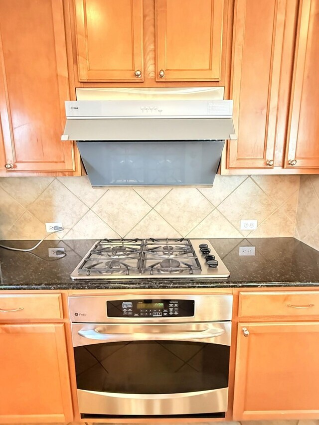2214 Jurgensen Ln, Sugar Land, TX 77479 - kitchen featuring appliances with stainless steel finishes, exhaust hood, dark stone countertops, and decorative backsplash