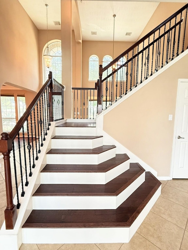 2214 Jurgensen Ln, Sugar Land, TX 77479 - stairs featuring a chandelier, tile patterned flooring, arched walkways, and high vaulted ceiling
