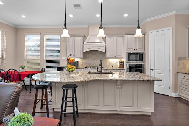 31304 New Forest Park Ln, Spring, TX 77386 - kitchen featuring backsplash, a kitchen island with sink, a kitchen breakfast bar, built in microwave, and light stone counters