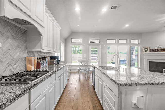 15 Eden Hollow Ln, Richmond, TX 77406 - kitchen featuring stainless steel appliances, white cabinetry, light wood-style flooring, backsplash, and an island with sink