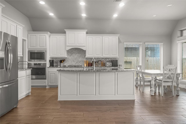 15 Eden Hollow Ln, Richmond, TX 77406 - kitchen with stainless steel appliances, lofted ceiling, decorative backsplash, wood finished floors, and white cabinetry