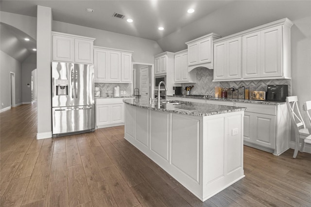 15 Eden Hollow Ln, Richmond, TX 77406 - kitchen featuring stainless steel appliances, arched walkways, a kitchen island with sink, wood finished floors, and recessed lighting