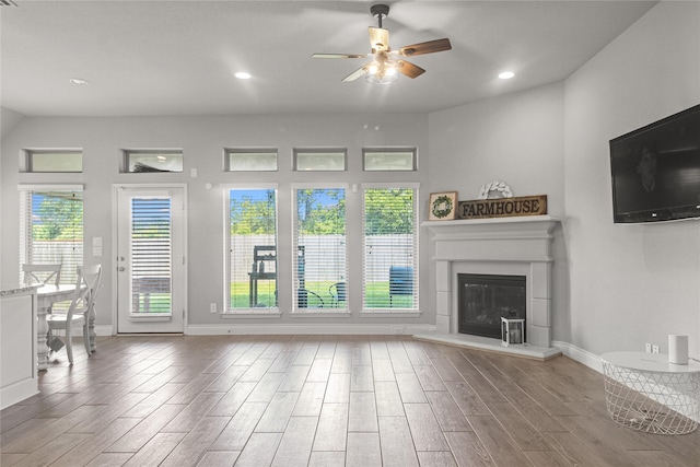 15 Eden Hollow Ln, Richmond, TX 77406 - unfurnished living room featuring a ceiling fan, wood finished floors, a glass covered fireplace, and recessed lighting