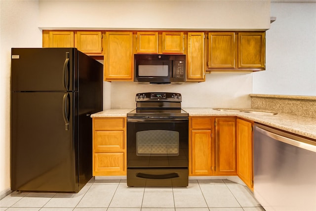 2121 El Paseo St Unit 1305, Houston, TX 77054 - kitchen with black appliances, light countertops, light tile patterned floors, decorative backsplash, and brown cabinetry