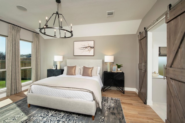 9402 Orchard Trl, Missouri City, TX 77459 - bedroom featuring a barn door, light wood-style floors, and a chandelier