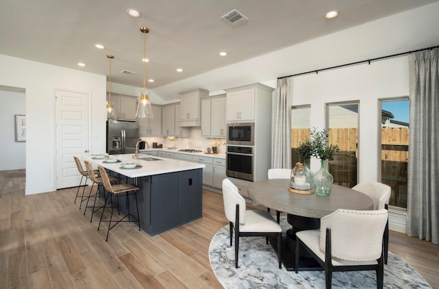 9402 Orchard Trl, Missouri City, TX 77459 - kitchen featuring appliances with stainless steel finishes, light countertops, an island with sink, a kitchen bar, and recessed lighting