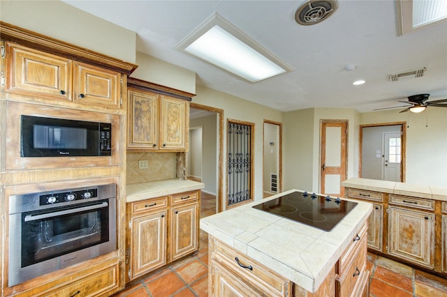 17522 Sorrel Ridge Dr, Spring, TX 77388 - kitchen with black appliances, tile counters, decorative backsplash, a center island, and a ceiling fan