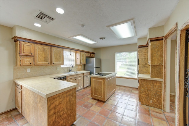 17522 Sorrel Ridge Dr, Spring, TX 77388 - kitchen with a center island, freestanding refrigerator, tasteful backsplash, a peninsula, and tile countertops