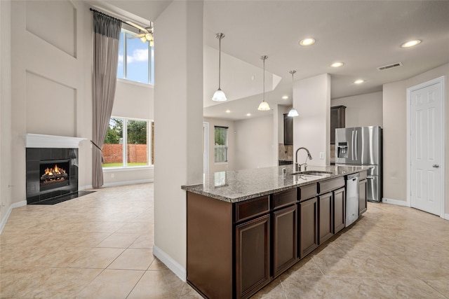 5227 Birch Falls Ln, Sugar Land, TX 77479 - kitchen featuring appliances with stainless steel finishes, light stone countertops, dark brown cabinets, ceiling fan, and recessed lighting