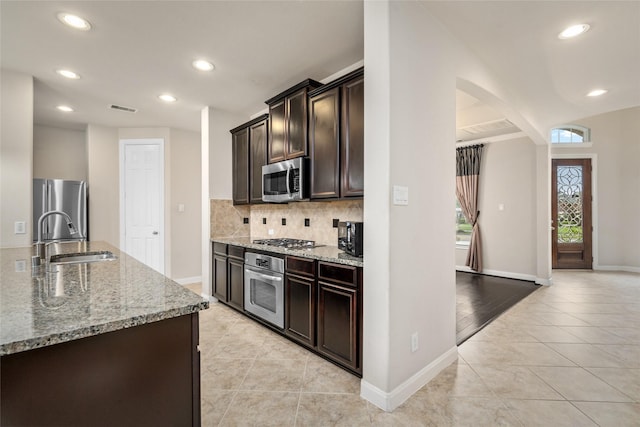 5227 Birch Falls Ln, Sugar Land, TX 77479 - kitchen featuring appliances with stainless steel finishes, light tile patterned flooring, arched walkways, light stone countertops, and recessed lighting