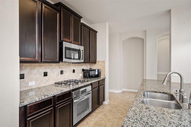 5227 Birch Falls Ln, Sugar Land, TX 77479 - kitchen featuring appliances with stainless steel finishes, tasteful backsplash, light stone counters, dark brown cabinetry, and light tile patterned floors