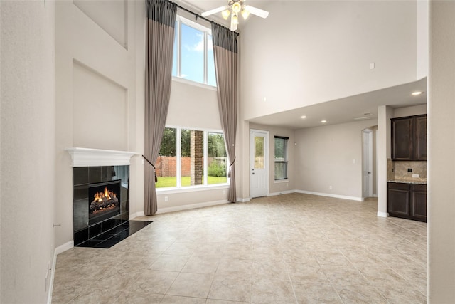 5227 Birch Falls Ln, Sugar Land, TX 77479 - unfurnished living room with a high ceiling, a tiled fireplace, ceiling fan, light tile patterned floors, and recessed lighting