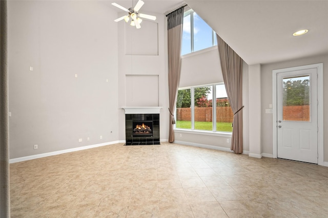 5227 Birch Falls Ln, Sugar Land, TX 77479 - unfurnished living room featuring healthy amount of natural light, a towering ceiling, a tiled fireplace, a ceiling fan, and light tile patterned floors