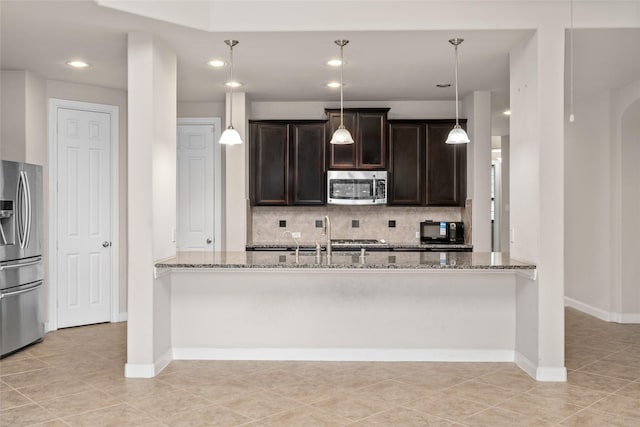 5227 Birch Falls Ln, Sugar Land, TX 77479 - kitchen featuring appliances with stainless steel finishes, light stone counters, tasteful backsplash, dark brown cabinetry, and recessed lighting