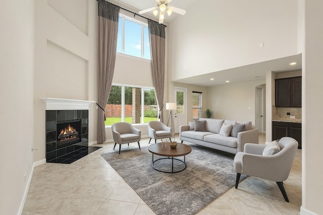 5227 Birch Falls Ln, Sugar Land, TX 77479 - living area featuring a tiled fireplace, a towering ceiling, healthy amount of natural light, ceiling fan, and arched walkways