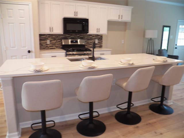 4218 Sorsby Dr, Houston, TX 77047 - kitchen with black microwave, stainless steel range, light wood-style flooring, white cabinetry, and backsplash