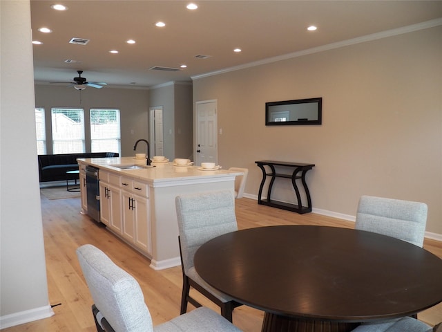 4218 Sorsby Dr, Houston, TX 77047 - kitchen with white cabinetry, an island with sink, light wood-style floors, ornamental molding, and recessed lighting