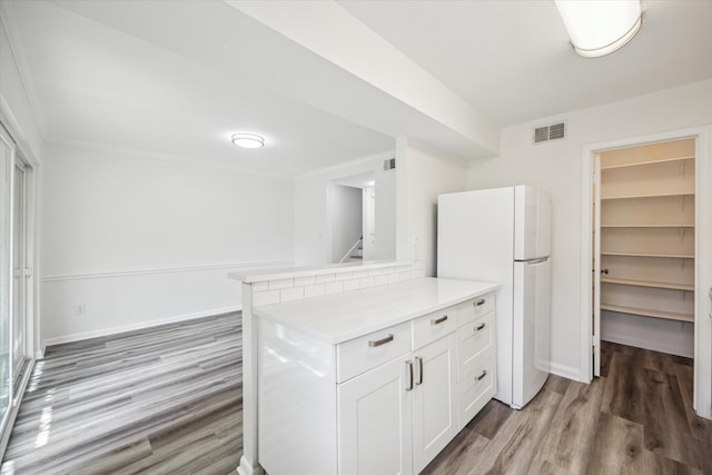 6451 Olympia Dr Unit 96, Houston, TX 77057 - kitchen with freestanding refrigerator, wood finished floors, white cabinetry, light countertops, and a peninsula