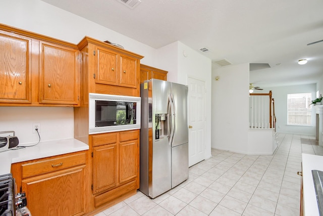 9338 Corner Oak Ln, Houston, TX 77036 - kitchen with stainless steel refrigerator with ice dispenser, built in microwave, light countertops, brown cabinetry, and light tile patterned floors