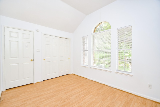 9338 Corner Oak Ln, Houston, TX 77036 - unfurnished bedroom with light wood-type flooring, multiple windows, lofted ceiling, and a closet