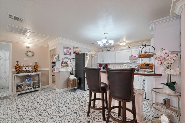 530 Frankie St Unit 1, Houston, TX 77015 - kitchen with freestanding refrigerator, a chandelier, white cabinetry, ornamental molding, and a breakfast bar area