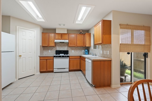 15506 Elm Leaf Pl, Cypress, TX 77429 - kitchen with white appliances, under cabinet range hood, backsplash, light countertops, and light tile patterned floors