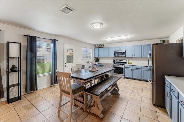 2830 Katybriar Ln, Katy, TX 77449 - kitchen featuring stainless steel appliances, light countertops, light tile patterned floors, and blue cabinets