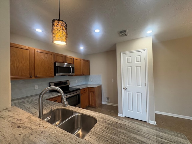 13693 Bighorn Trl, Willis, TX 77378 - kitchen featuring appliances with stainless steel finishes, brown cabinetry, tile patterned flooring, backsplash, and recessed lighting