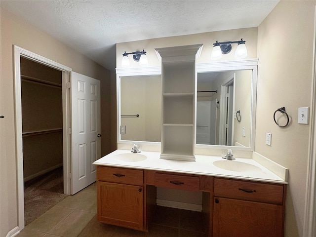 13693 Bighorn Trl, Willis, TX 77378 - full bathroom featuring double vanity, tile patterned flooring, a walk in closet, and a textured ceiling