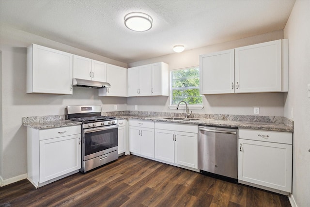 3209 Mccrarey Dr, Houston, TX 77088 - kitchen with stainless steel appliances, under cabinet range hood, white cabinetry, and dark wood-type flooring